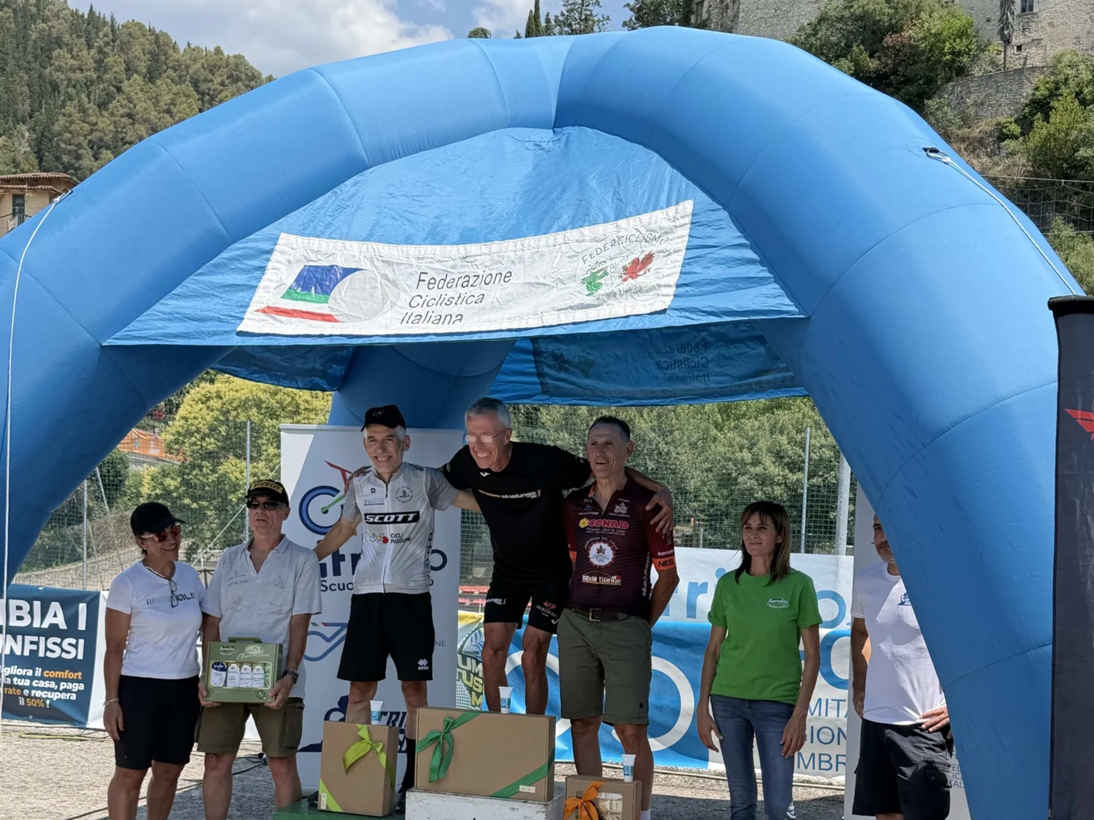Atleti in maglia bianca premiati sul podio con il borgo alle spalle