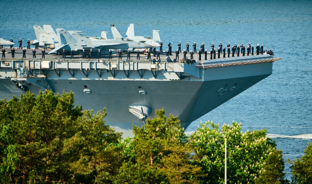 A Large Navy Ship With a Bunch of Fighter Jets on Top of It