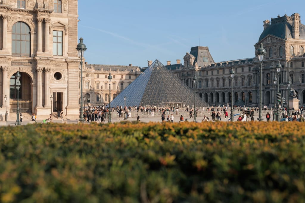 Louvre Museum with Glass Pyramid and Gardens on a Sunny Day with People Gathering