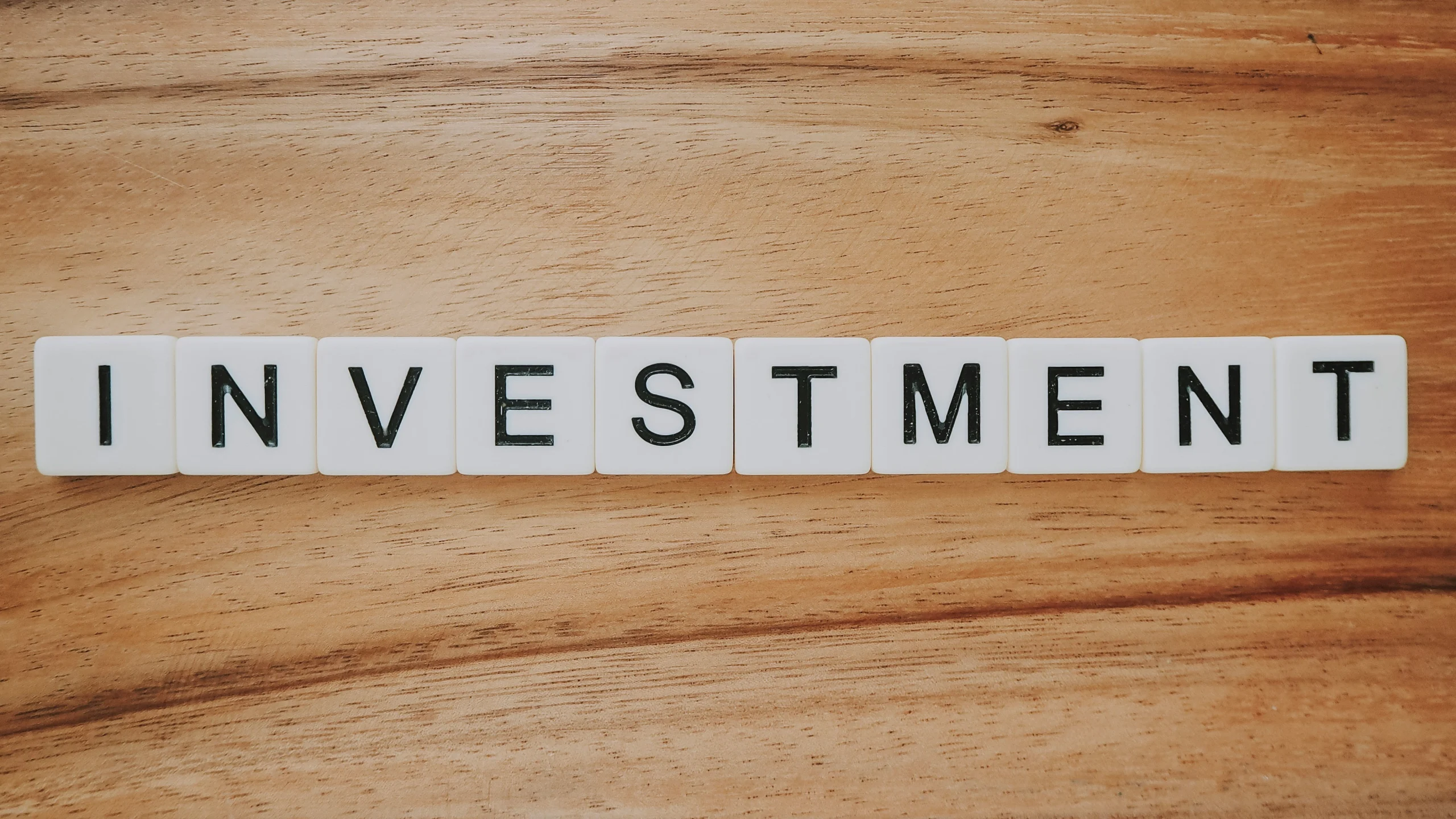 The word 'INVESTMENT' in capital letters on a wooden table.