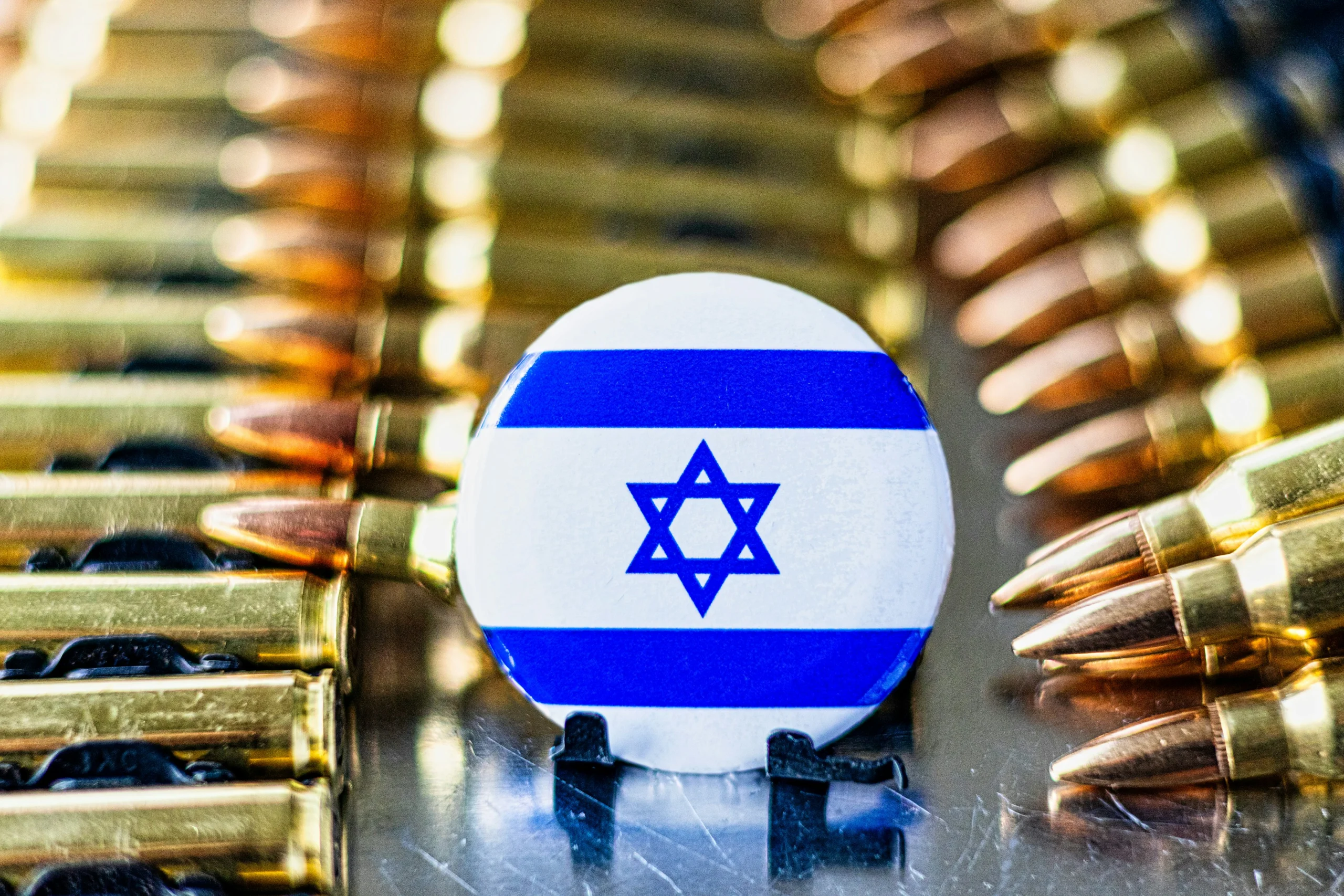 Close-up of a pile of bullet casings with an Israeli flag positioned in the center.