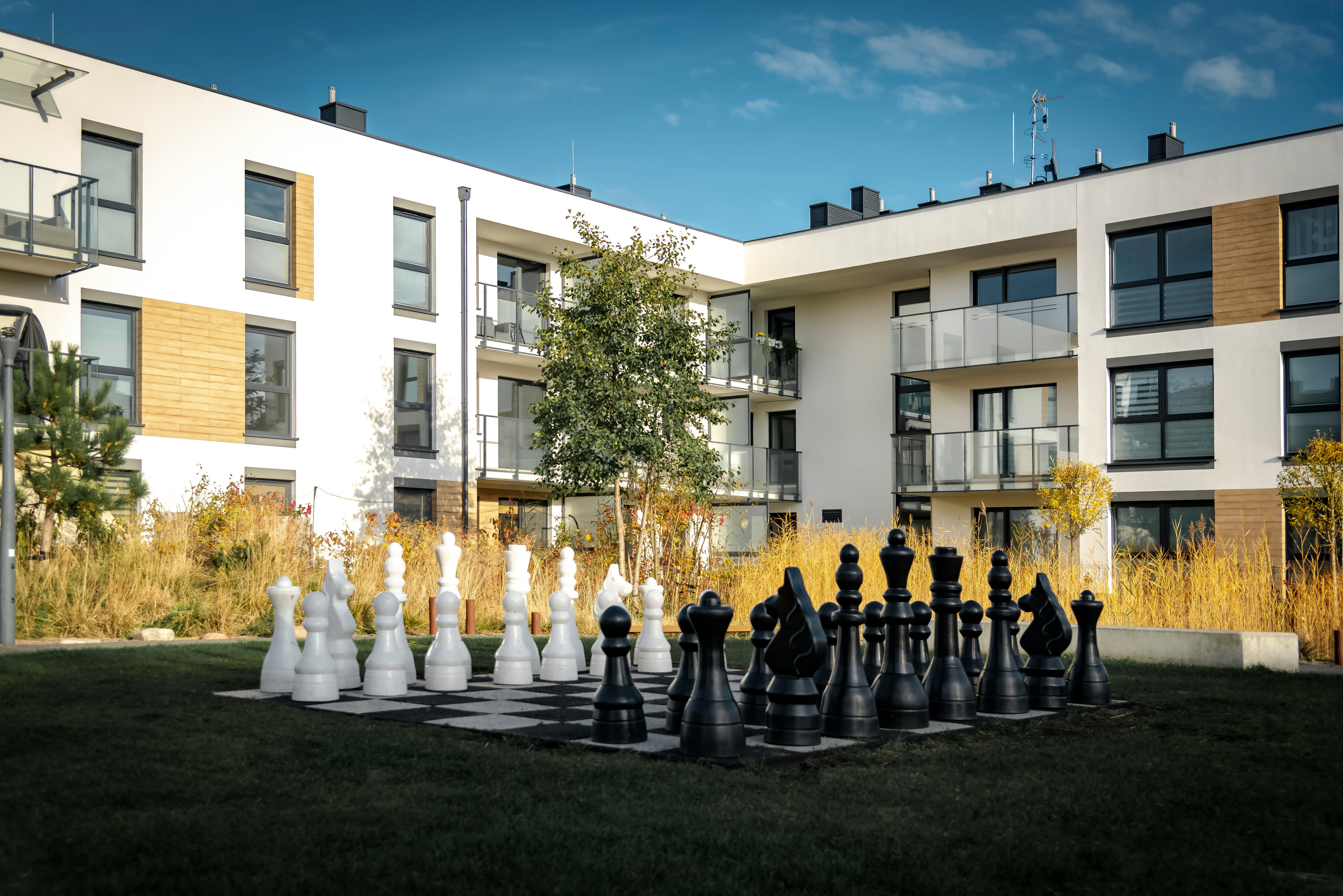 Giant chess set in a courtyard with modern buildings.