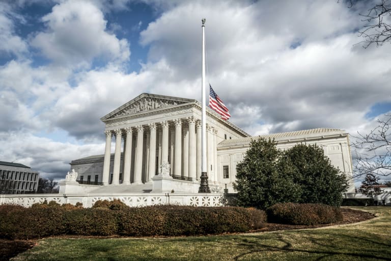 US Supreme Court building with a flag on top of it.