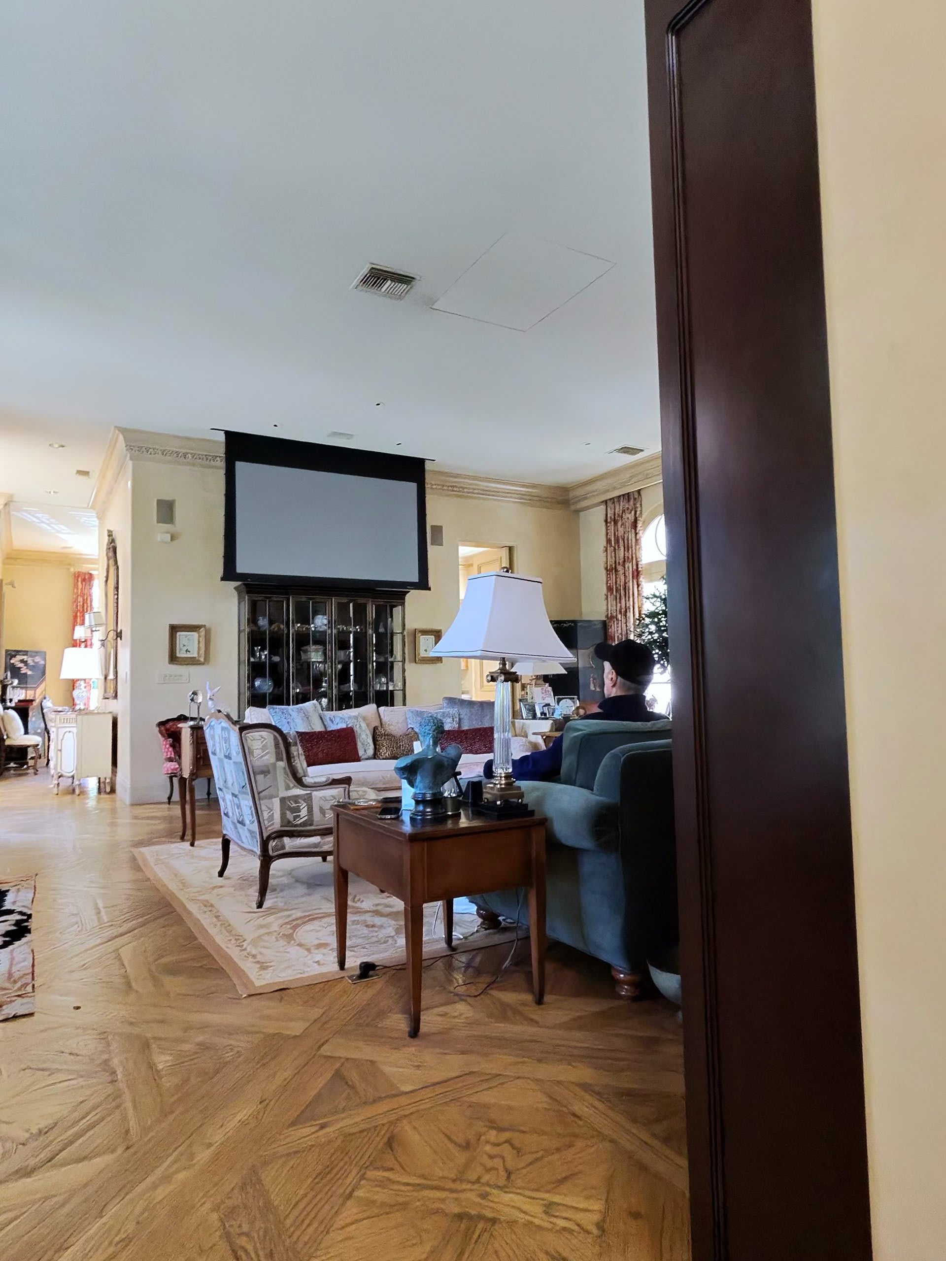 Motorized projection screen lowering into a formal living room for movie night — Ermine Smart Home, Los Angeles