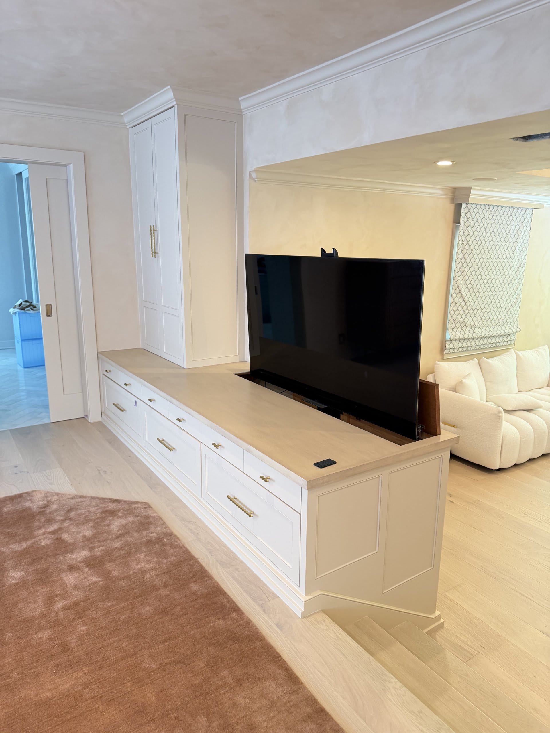 Wall-mounted television above a custom media console in a bright living room — Ermine Smart Home, Los Angeles