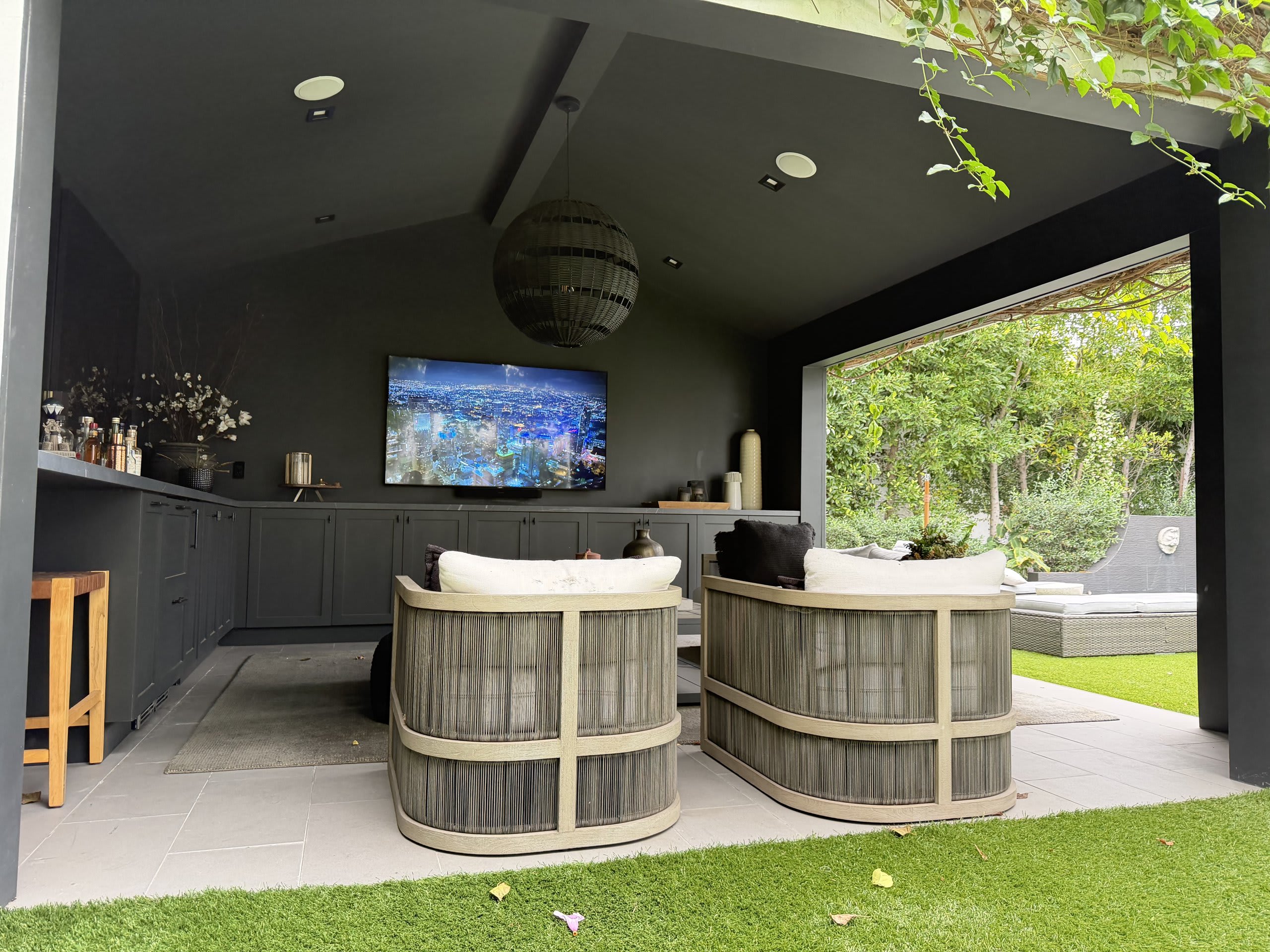 Outdoor television under a covered patio with lounge seating beside the pool — Ermine Smart Home, Los Angeles