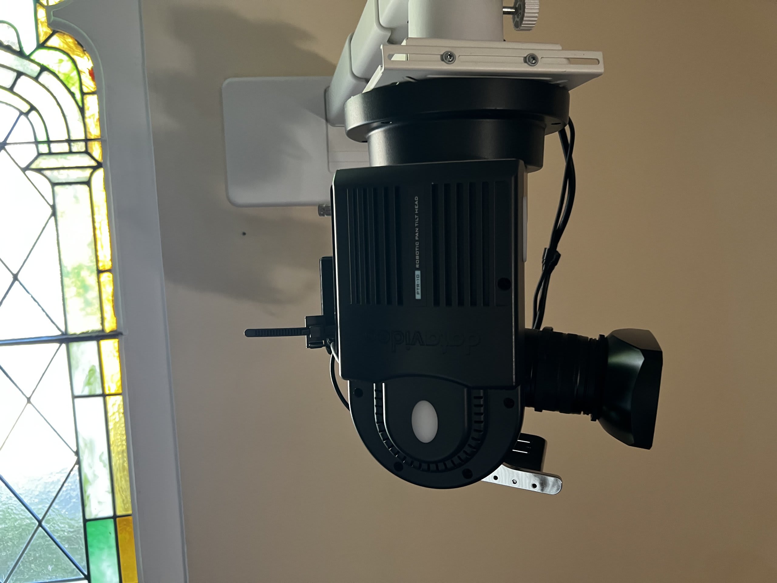 Robotic PTZ camera near a stained-glass window streaming a service — Ermine Smart Home, Los Angeles