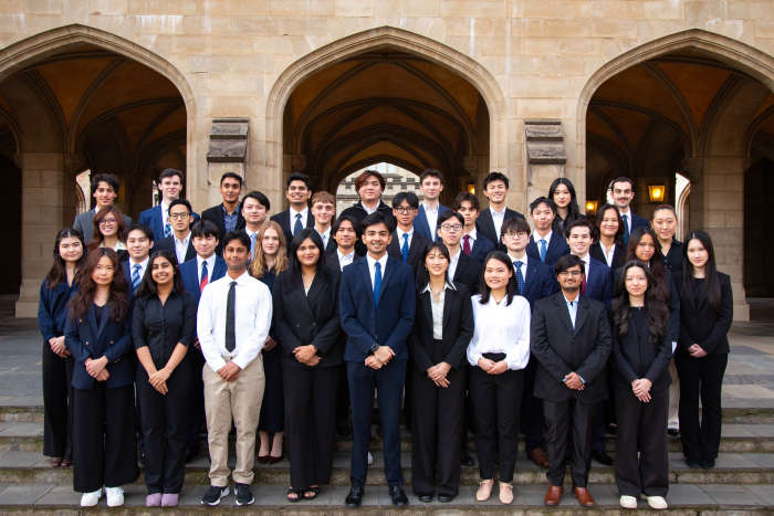 Committee members in formal dress standing in front of sandstone building