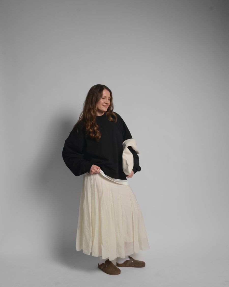 365.APParel Oversize Sweatshirt Black — woman, full body three-quarter view, smiling, tote bag, pleated maxi skirt, studio