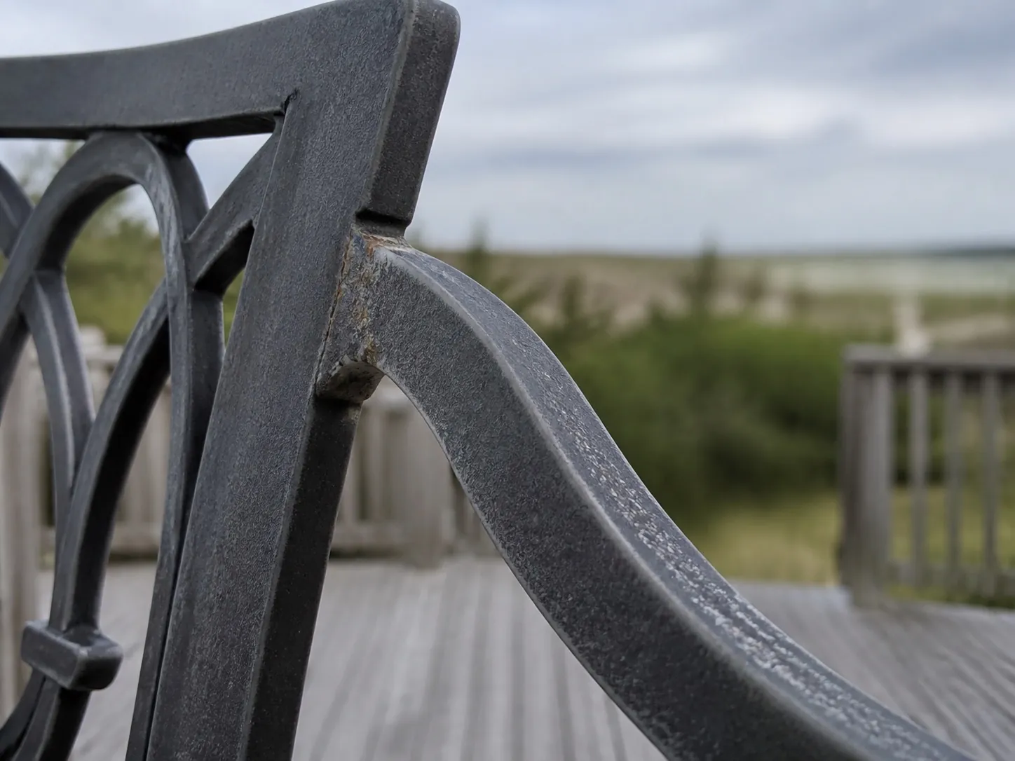 Close-up of coating wear on a metal patio chair at a coastal property
