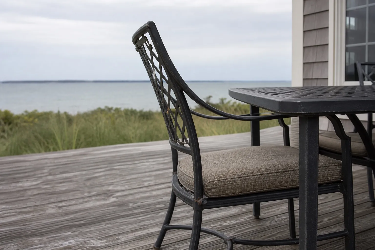 Metal patio dining furniture with visible coating wear on a coastal deck