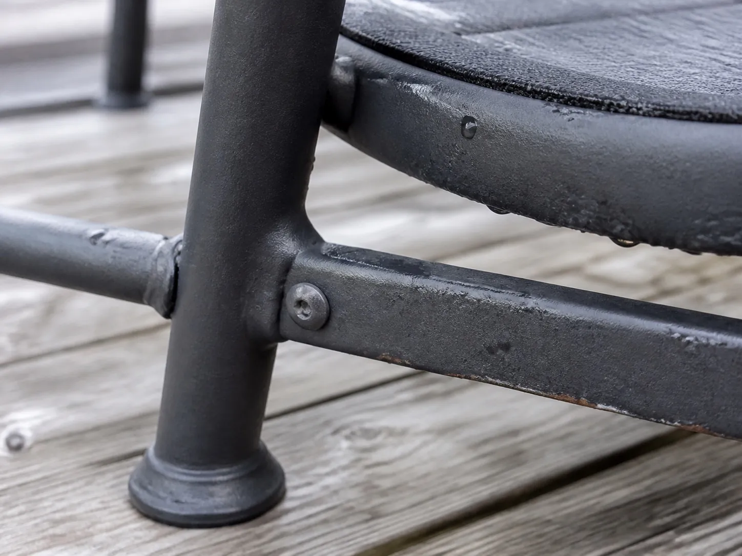 Close view of a coated metal patio chair joint and lower frame during a visible-condition inspection