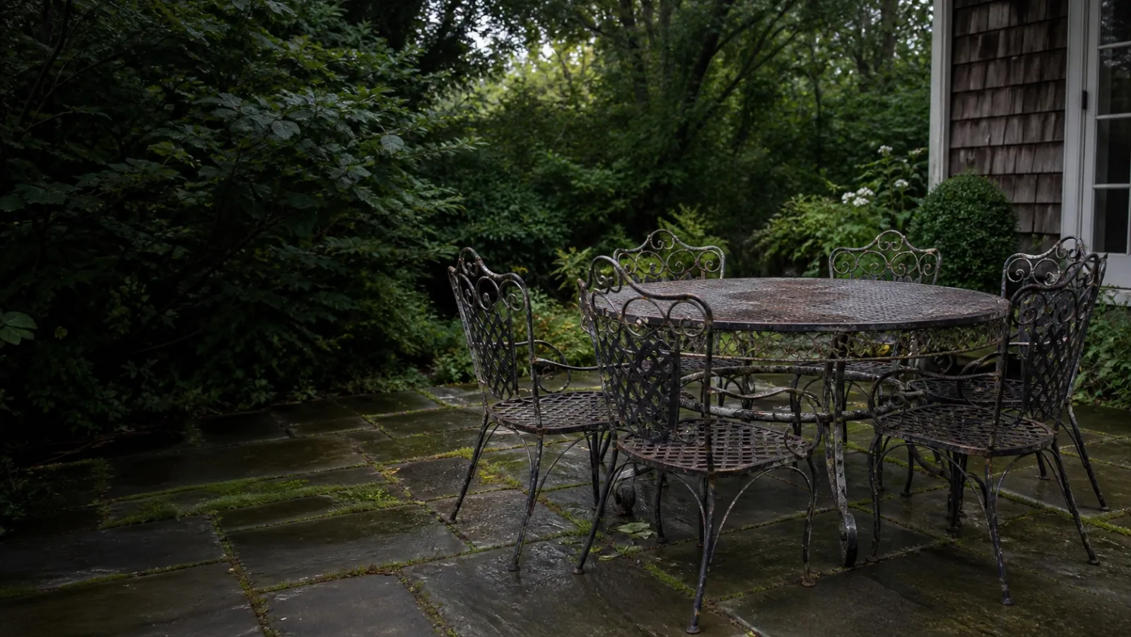 A weathered wrought iron patio dining set in a New Jersey garden
