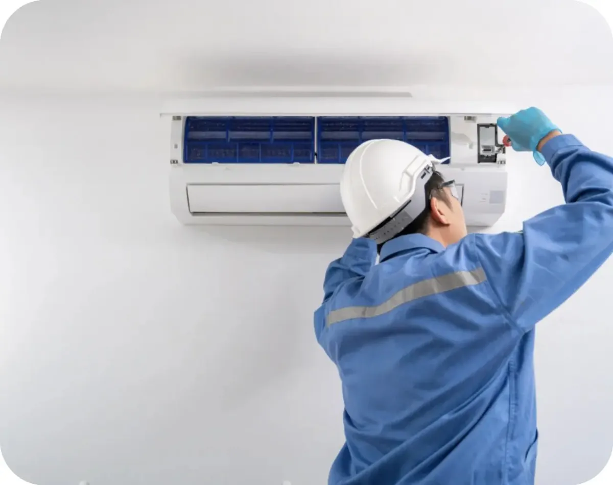 Technician servicing an air conditioner unit on a wall