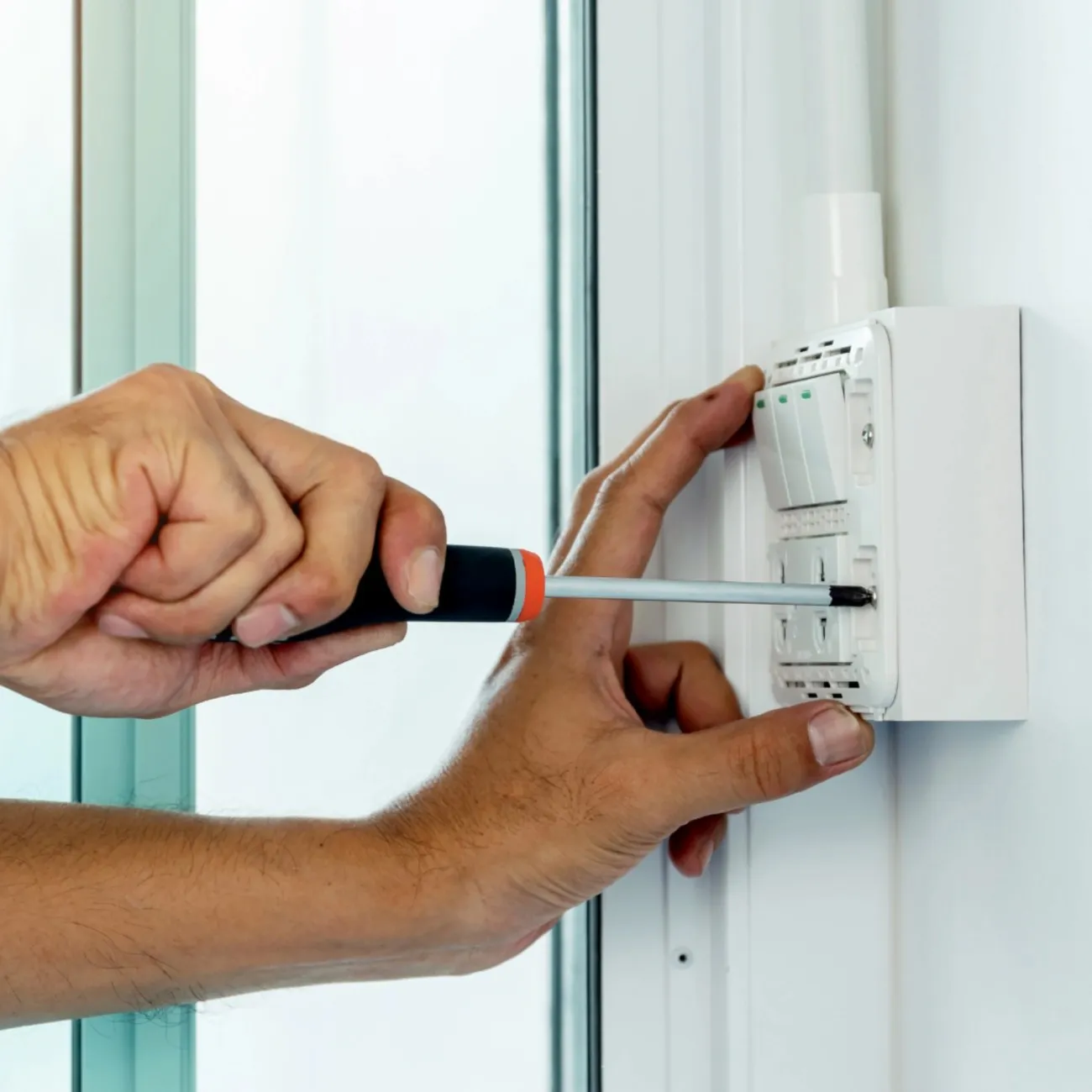Electrician using a screwdriver to fix an electrical socket