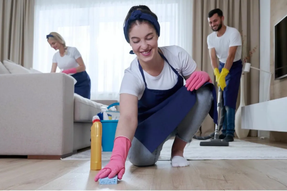 Professional cleaners working on a living room, scrubbing the floor and furniture