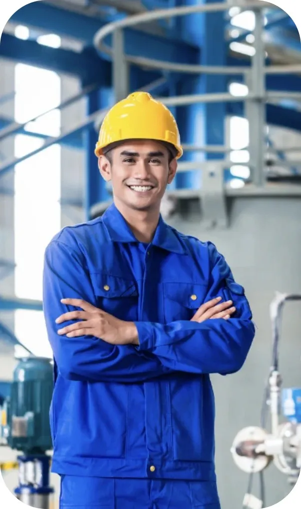 Smiling engineer in a hard hat and blue uniform with arms crossed