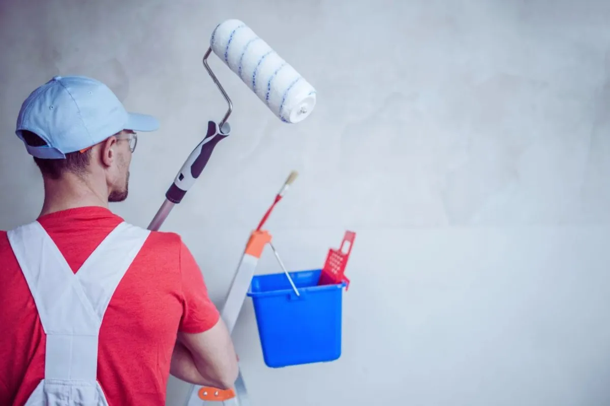 Painter applying a fresh coat of paint to a home’s interior wall with a roller