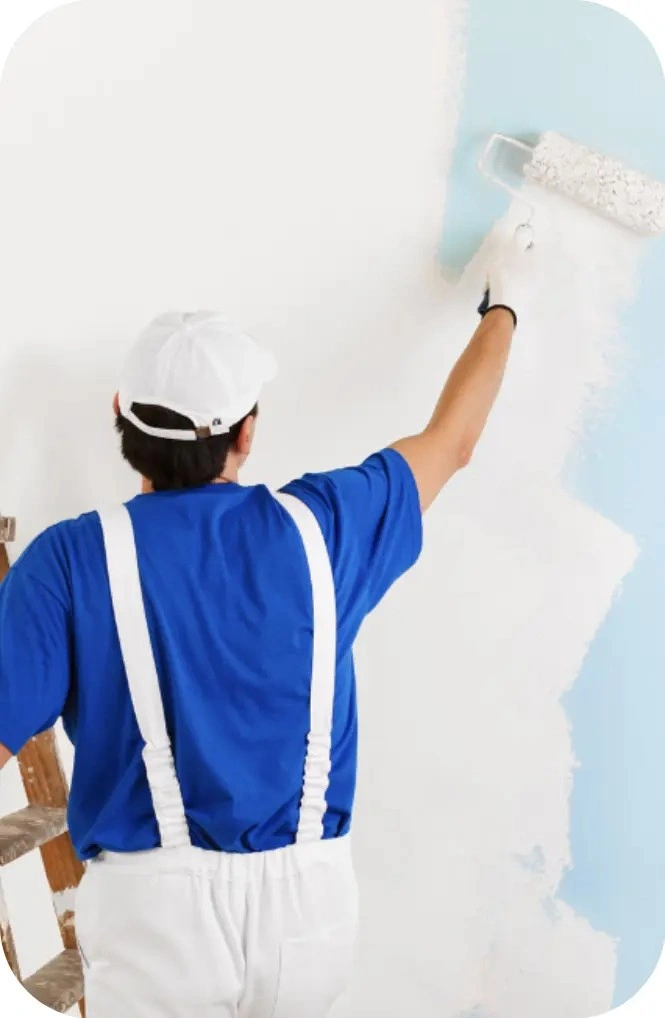 Painter applying white paint to a wall with a roller
