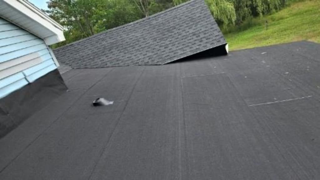 Newly installed black roofing felt on house, showing a pre-shingle stage