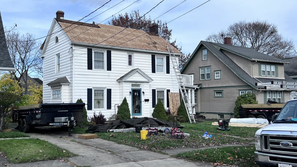 Pre-renovation scene with a dumpster at a white suburban home, exemplifying preparation for extensive roofing work.