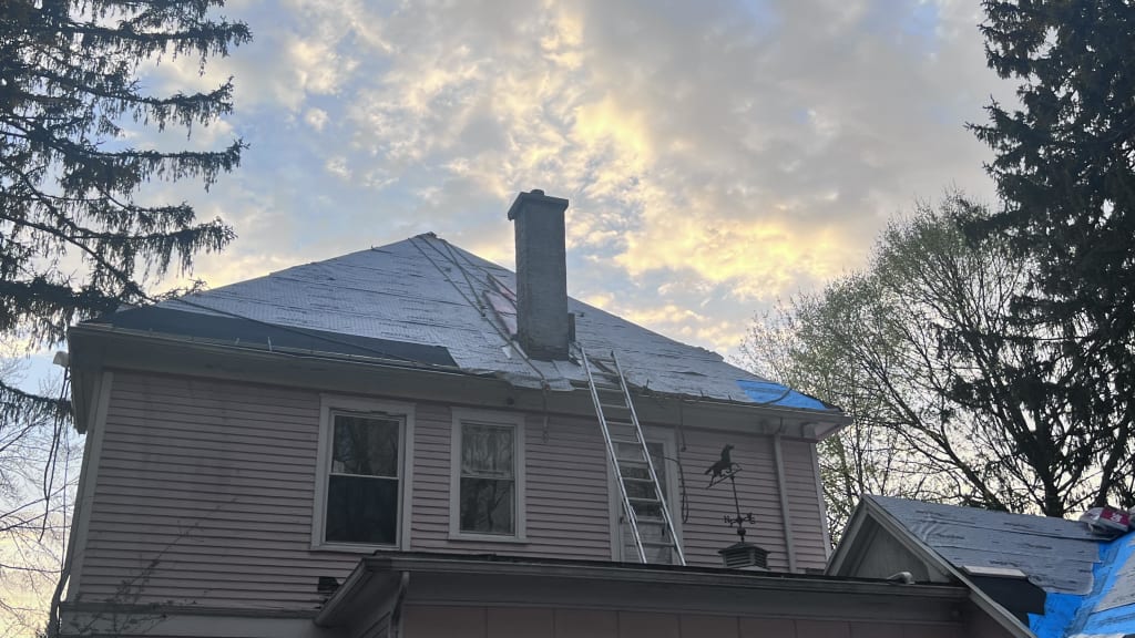 Dawn lighting captures roofers applying synthetic underlayment on a home, a critical step for durable roofing.