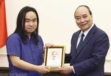 Chủ tịch nước Nguyễn Xuân Phúc tặng ảnh Chủ tịch Hồ Chí Minh cho dịch giả trẻ Nguyễn Bình. (Ảnh: Thống Nhất/TTXVN)