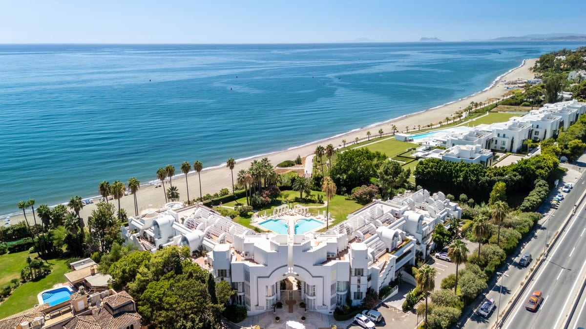 Luchtfoto van witte woningen langs een strand en de blauwe zee