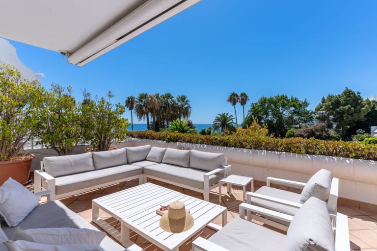 Overdekt terras met witte loungeset en palmen