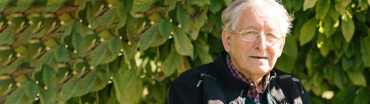 Ted Simon staat voor een struik