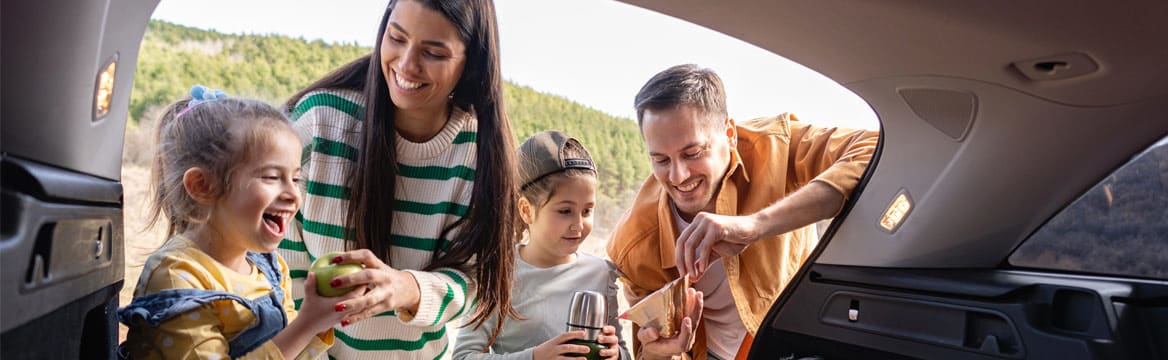 gezin met kinderen is aan het eten bij de auto