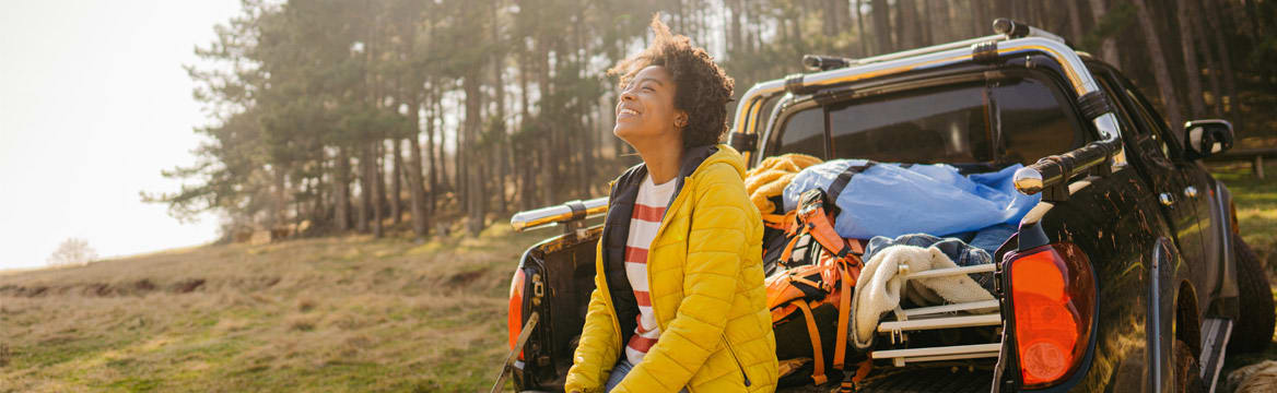 vrouw bij auto in natuurlijke omgeving
