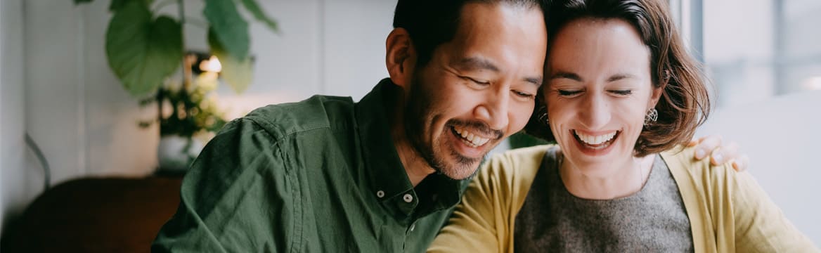 man en vrouw zitten lachend aan tafel met pen en papier