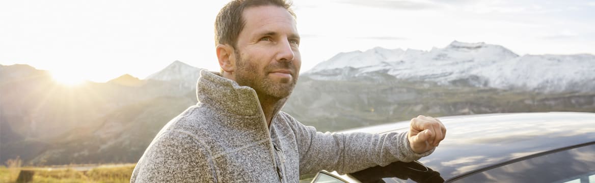 man staat bij auto bij de bergen
