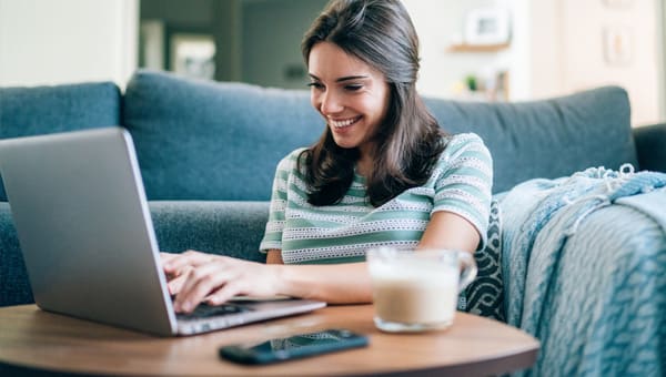 Vrouw aan tafel met laptop en koffie