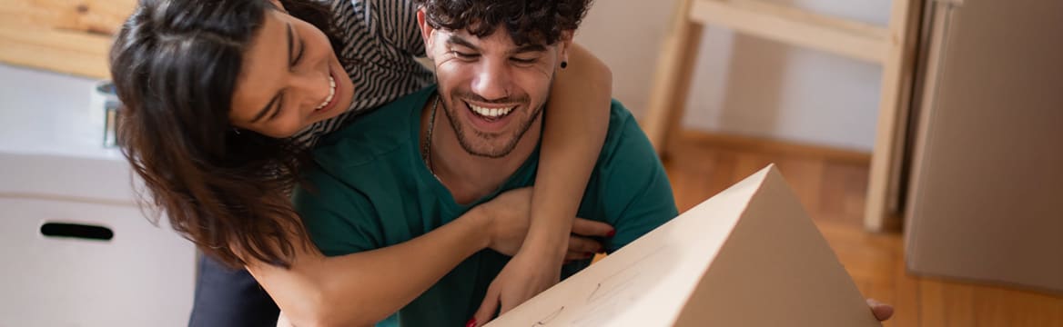 man en vrouw lachen terwijl ze aan het verhuizen zijn