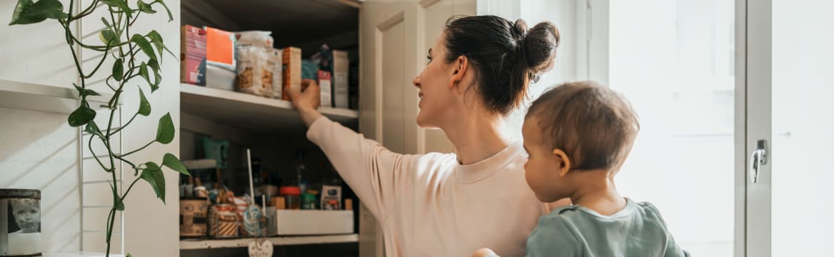 vrouw pakt iets uit voorraadkast met kind