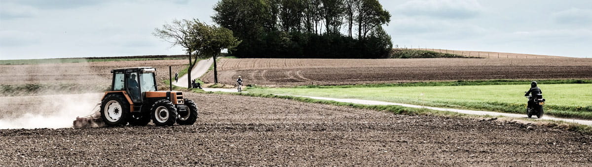 Motor rijdt door landschap met tractor