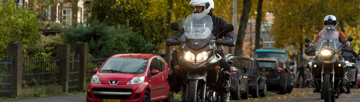 Twee motorrijders rijden door een woonwijk