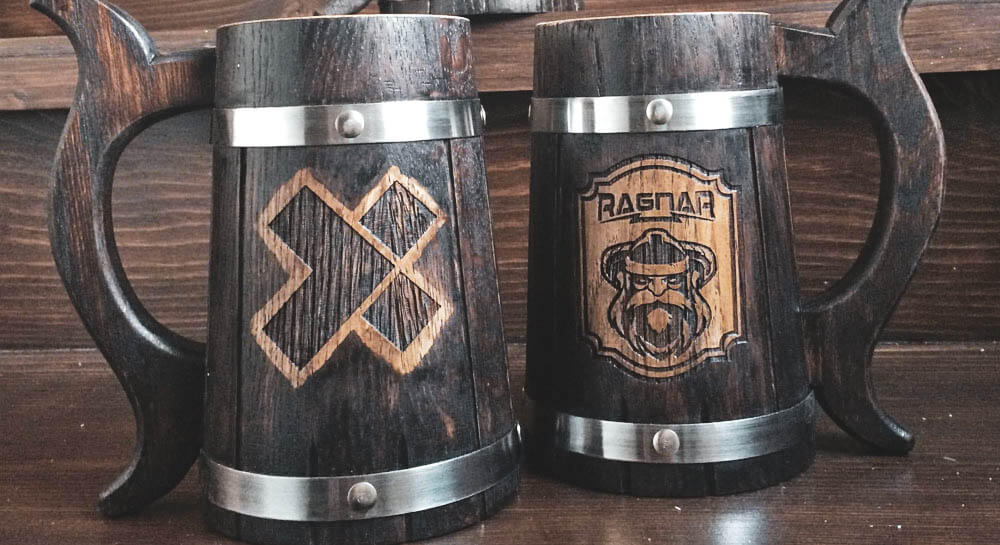 two wooden mugs with the House Ragnar and X-Team logos printed on their sides