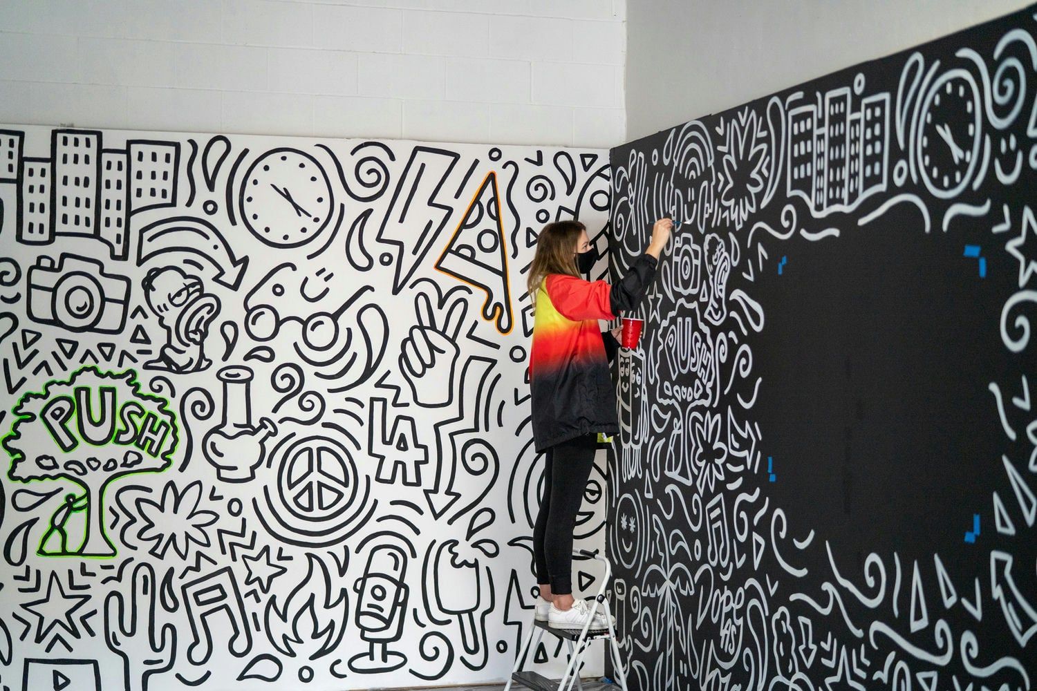  An artist painting a vibrant mural on a wall covered with intricate doodles and designs, showcasing creative expression and urban art