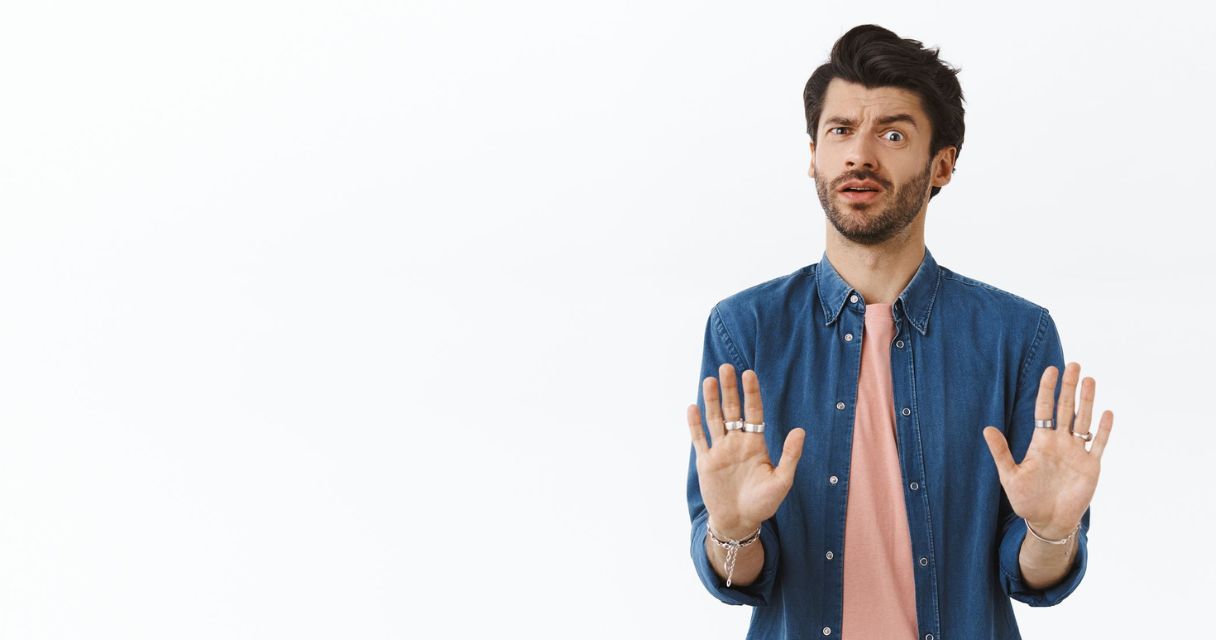 A man with a surprised expression holding his hands up in a "stop" gesture, conveying shock or caution