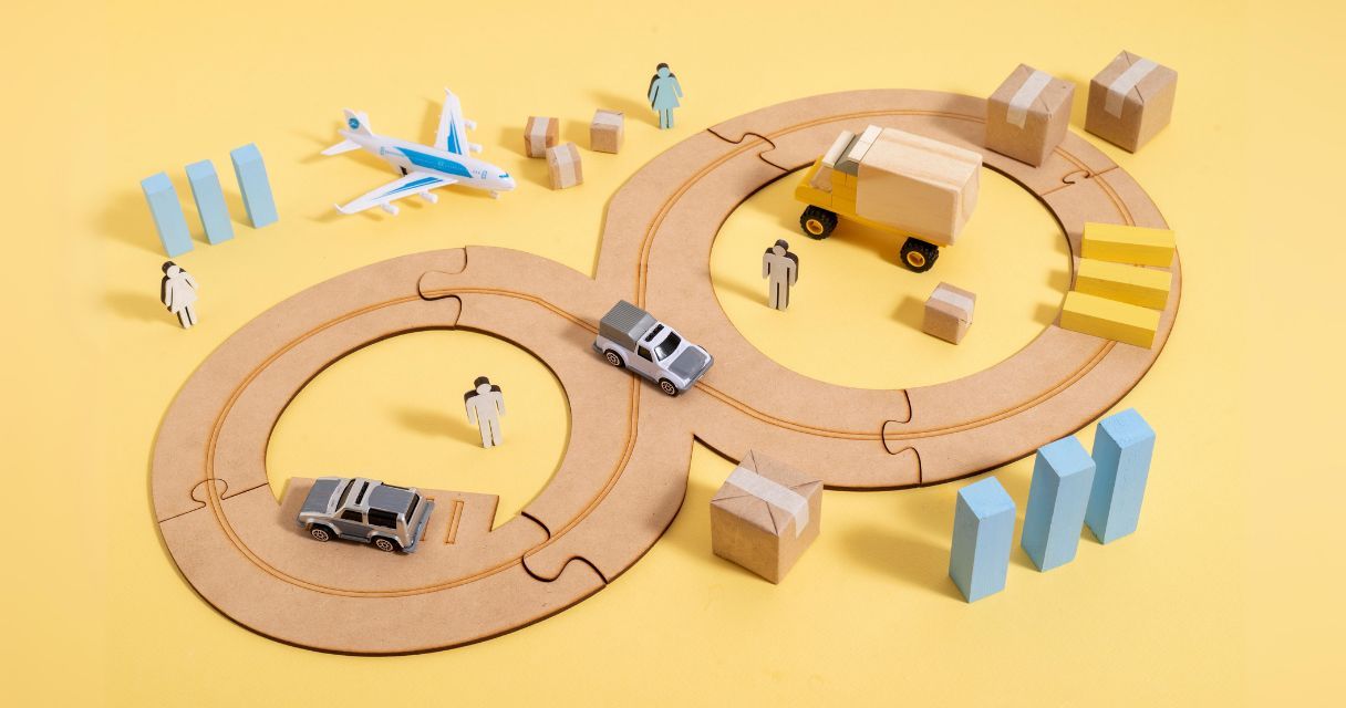 A conceptual representation of a supply chain with toy vehicles (airplane, truck, and cars) on interconnected circular tracks, along with miniature people and packages, illustrating the movement and logistics involved in supply chain management.