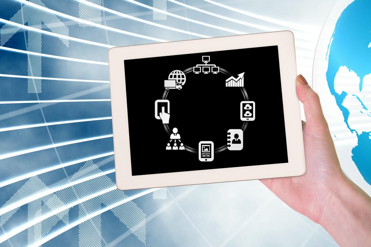 The image shows a hand holding a tablet displaying interconnected icons representing various business applications and processes, symbolizing digital transformation and integrated technology solutions.
