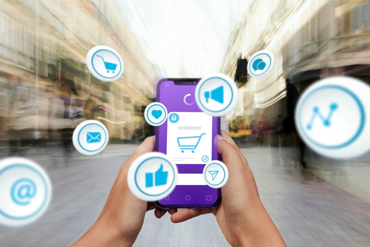 The image portrays a person holding a smartphone in a bustling city street, with various digital icons representing social media and e-commerce functions floating around the phone, symbolizing the integration of mobile technology with everyday activities.
