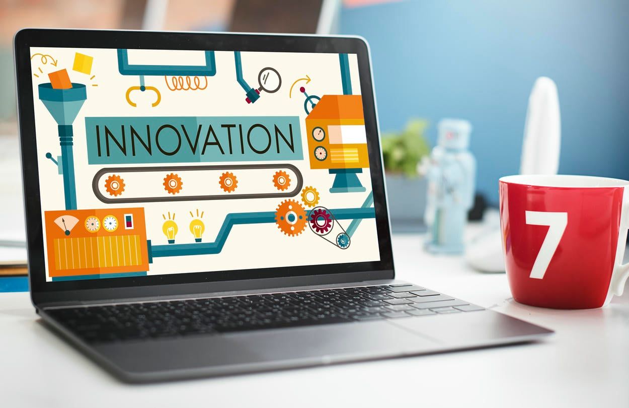 This image shows a laptop screen with the word "INNOVATION" surrounded by gears, symbolizing creative processes and technological advancement.