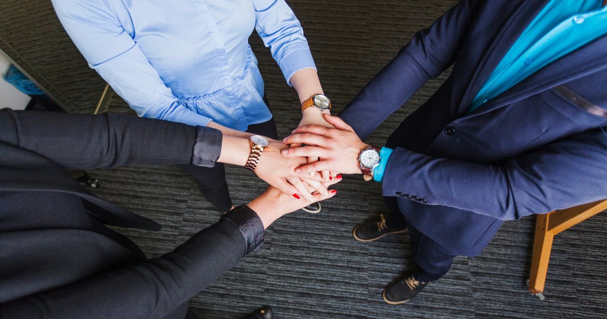 People standing in office holding hands together