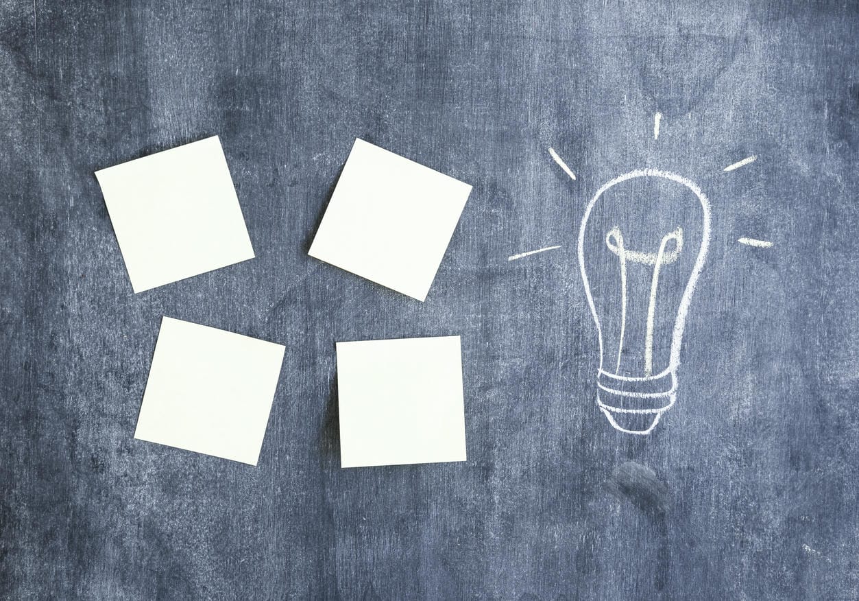 Blank adhesive notes and light bulb drawn on chalkboard