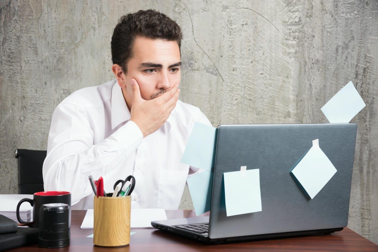 Businessman looking at laptop while holding his mouth at the office desk