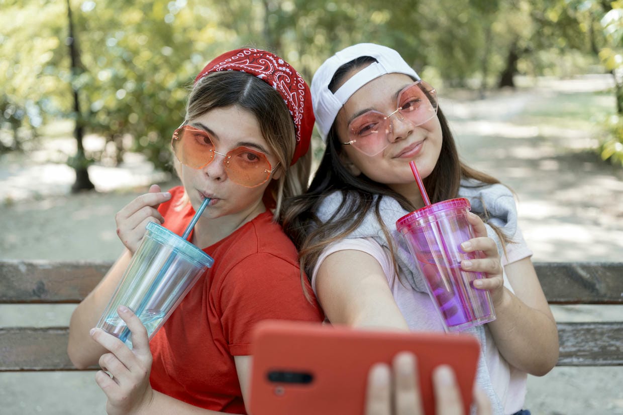 Medium shot girls taking selfie with drinks